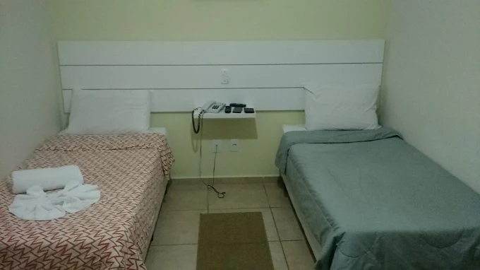 Quarto com duas camas de solteiro, telefone na cabeceira e tapete